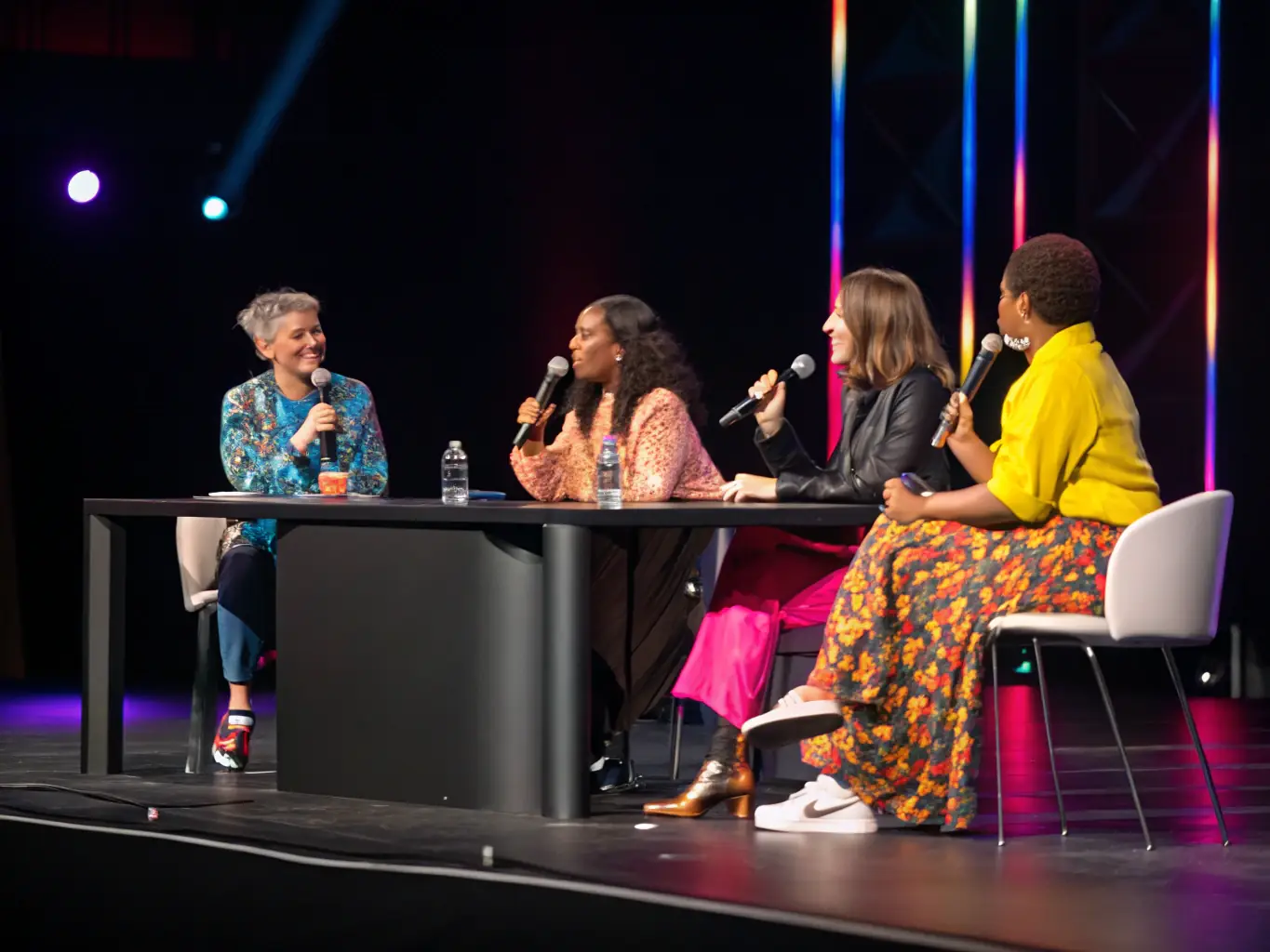 A photograph of a panel discussion in progress, featuring diverse speakers and a moderator, highlighting the interactive nature of the session.